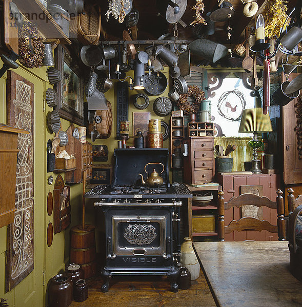 Alte Küchenutensilien und Formen aus Zinn hängen von der Decke in einer Landhausküche