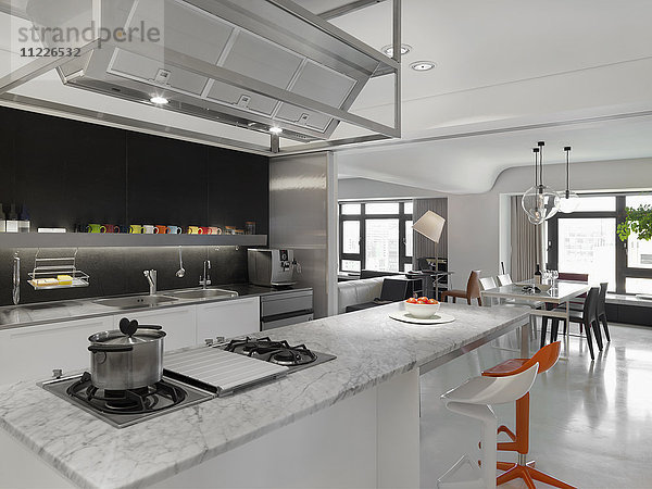 Moderne Küche mit orangefarbenen und weißen Barhockern