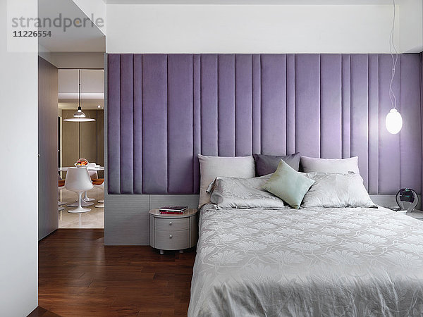 Elegantes modernes Schlafzimmer mit lila gepolsterter Wand
