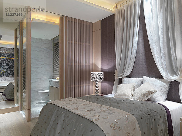 Elegantes Schlafzimmer mit Vorhängen über dem Bett