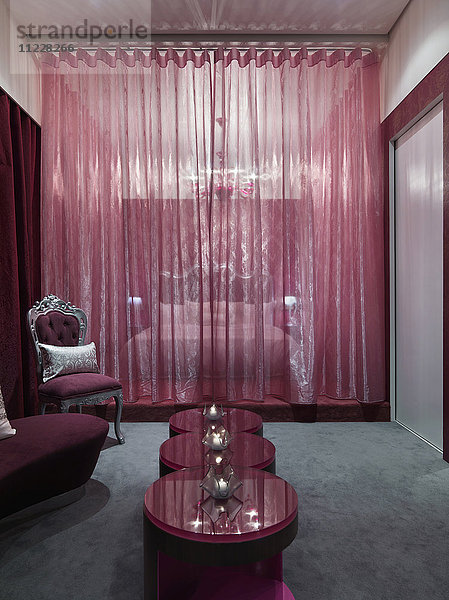 Schickes Schlafzimmer mit rosa Glascouchtisch und grauem Teppich