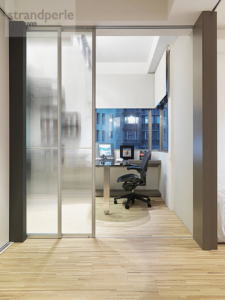 Modernes Heimbüro mit Parkettboden und Glasschiebetüren