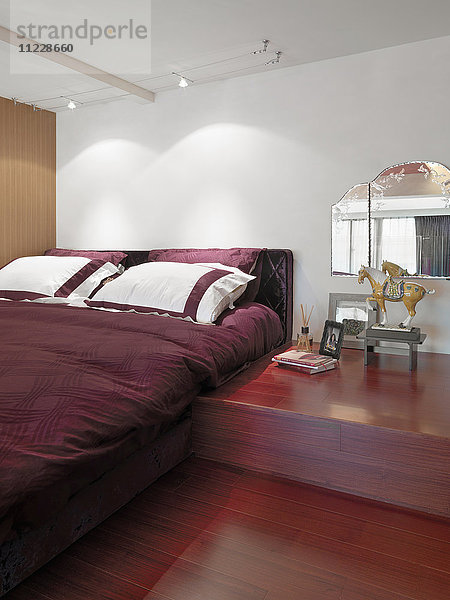 Rotes Bett und Hartholzboden im modernen Schlafzimmer