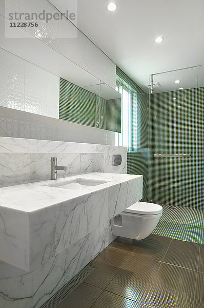 Waschbecken und Arbeitsplatte aus Marmor und Dusche mit Mosaikfliesen