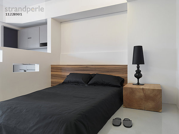 Einfaches modernes Schlafzimmer mit schwarzem Bett und Lampe