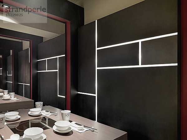 Schwarze Wand mit eingebauten Lichtern im asiatischen Esszimmer