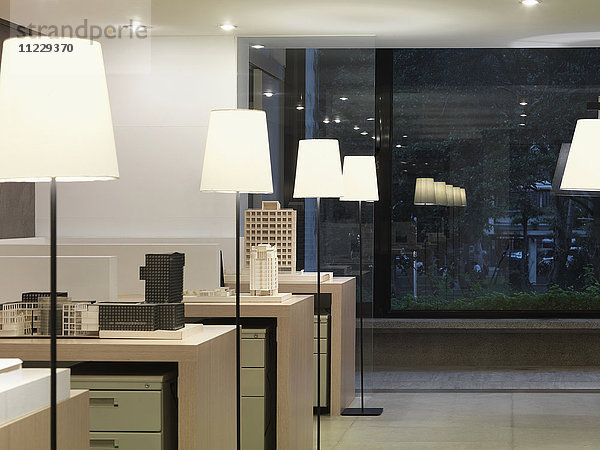 Sich wiederholende Lampen im modernen Büro bei Nacht
