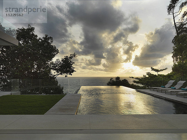Swimmingpool vor einem modernen Haus bei Sonnenuntergang