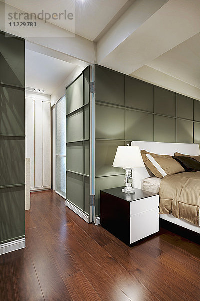 Braunes Bett in modernem Schlafzimmer mit grüner Akzentwand