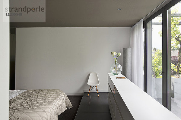 Blick auf ein abgeschnittenes Bett entlang eines großen Fensters im Schlafzimmer eines modernen Hauses