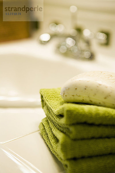 Stapel grüner Handtücher mit Seife auf dem Badezimmertisch