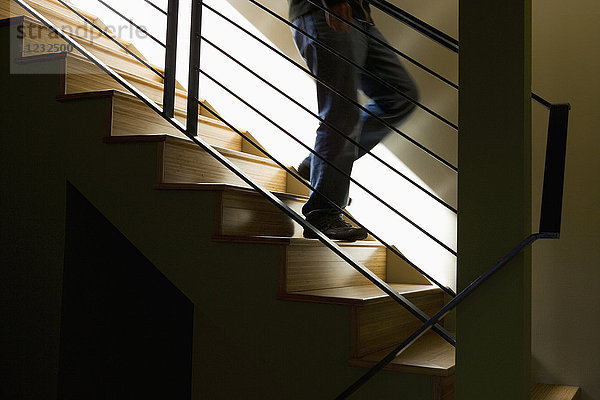 Stimmungsvolles Detail einer Person  die eine moderne Treppe hinabsteigt