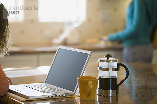 Junge Frau  die morgens Kaffee trinkt und an ihrem Laptop arbeitet
