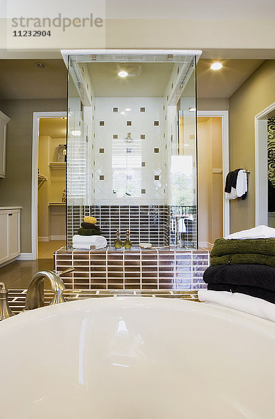 Bild von Badewanne und Handtüchern mit Dusche im Hintergrund.