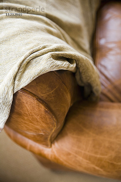 Detail einer Ledercouch mit Decke.