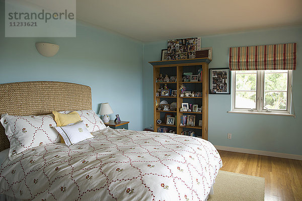 Bett mit geblümter Bettdecke in blauem Schlafzimmer
