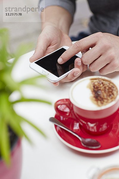 Person mit Smartphone und Kaffee