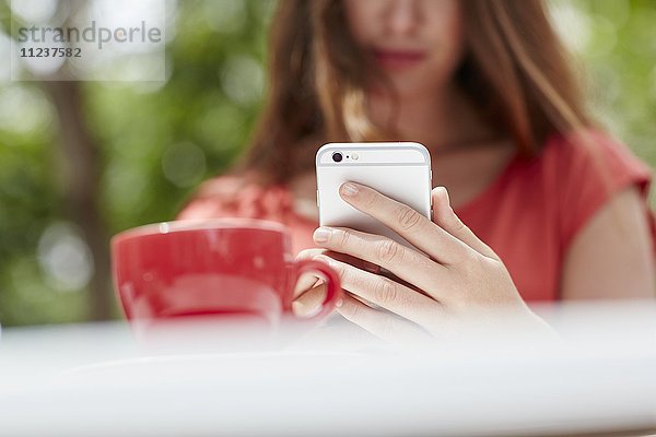 Frau benutzt Smartphone mit Kaffee