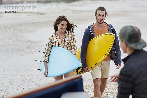 Junges Paar am Strand mit Surfbrettern