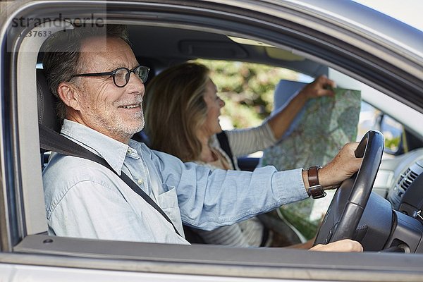 Älterer Mann im Auto  Frau hält Karte
