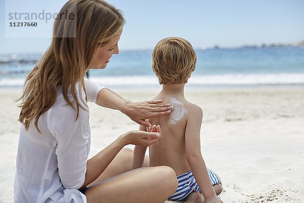 Mutter trägt ihrem Sohn Sonnencreme auf