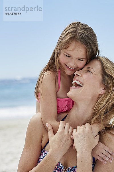 Mutter und Tochter lachend am Strand