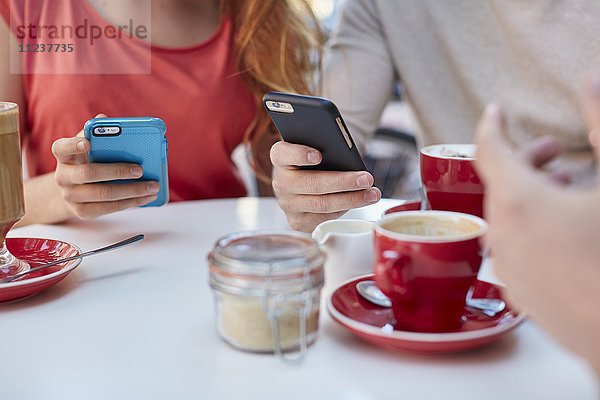 Junge Menschen im Café nutzen Smartphones