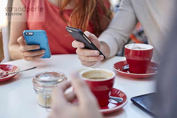 Junge Menschen im Café nutzen Smartphones