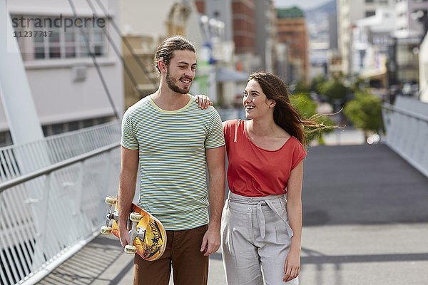 Paar geht  Mann trägt Skateboard