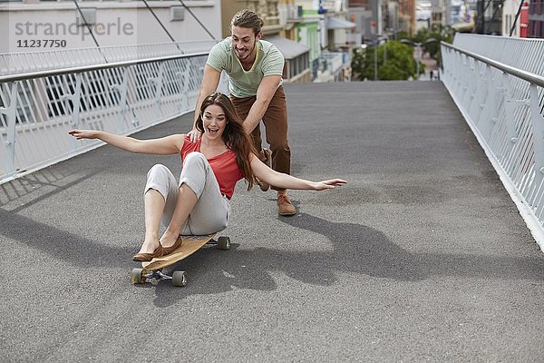 Frau auf Skateboard  Mann schiebend