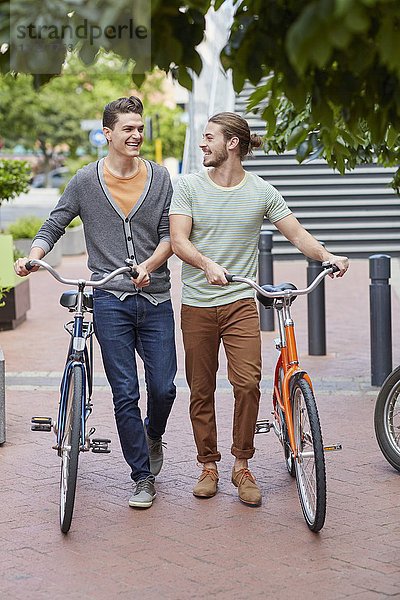 Zwei junge Männer  die Fahrräder schieben