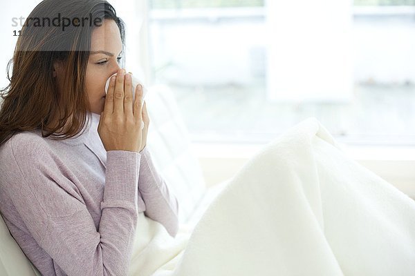 Junge Frau im Bett mit Erkältung