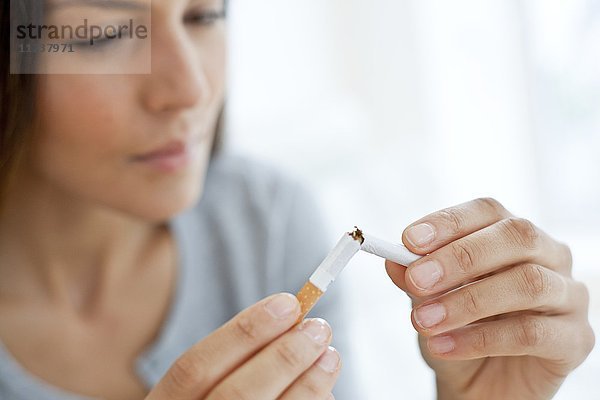 Junge Frau bricht Zigarette in der Hälfte