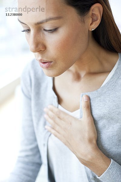 Junge Frau mit Hand auf der Brust