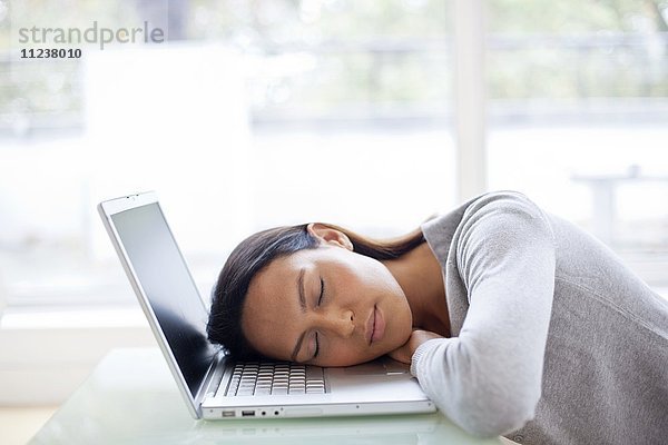 Junge Frau schlafend am Laptop