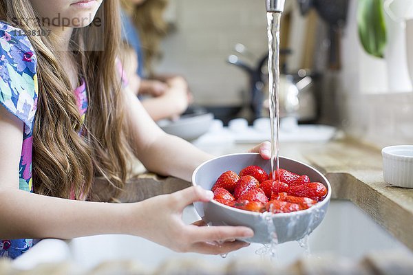 Mädchen wäscht frische Erdbeeren