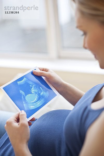 Schwangere Frau schaut auf Baby-Scan