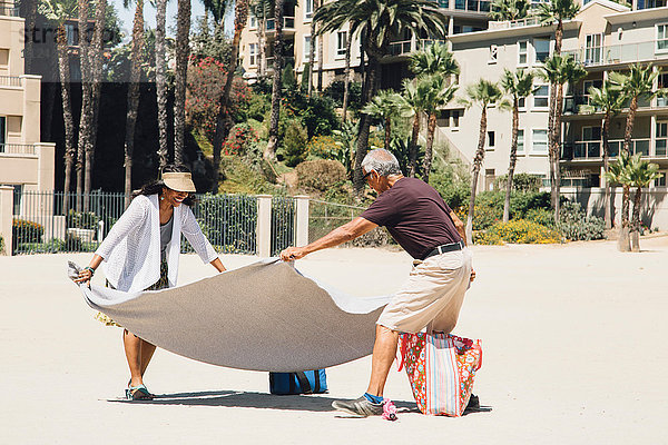 Älteres Ehepaar am Strand  legt Decke zum Picknick aus  Long Beach  Kalifornien  USA