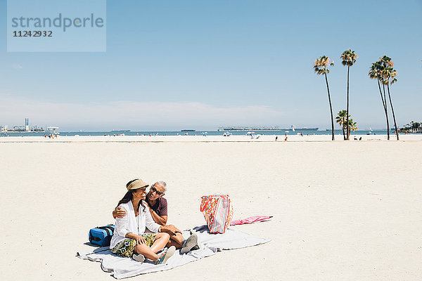 Älteres Ehepaar sitzt auf einer Picknickdecke am Strand  Long Beach  Kalifornien  USA