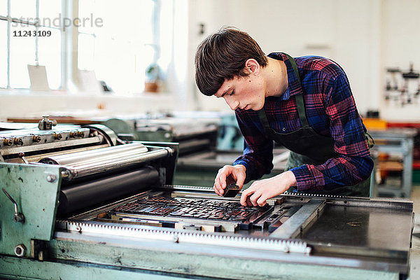 Junger Mann arbeitet an einer Buchdruckmaschine in einem Buchkunst-Workshop