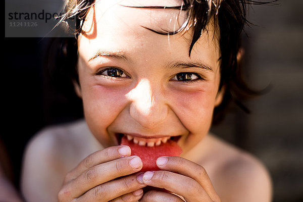 Glücklicher Junge isst am Sommertag Wassermelone