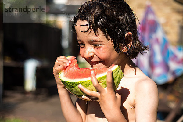Glücklicher Junge isst am Sommertag Wassermelone