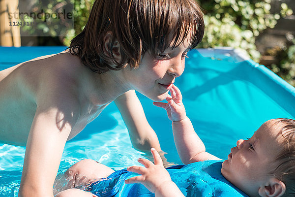Glückliche Brüder spielen am Sommertag im aufblasbaren Pool
