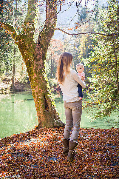 Rückansicht der Mutter und des Mädchens im Wald am Wasser