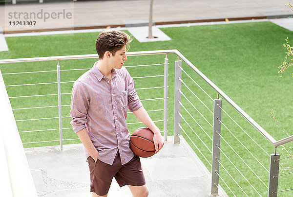 Junger Mann im Freien  hält Basketball