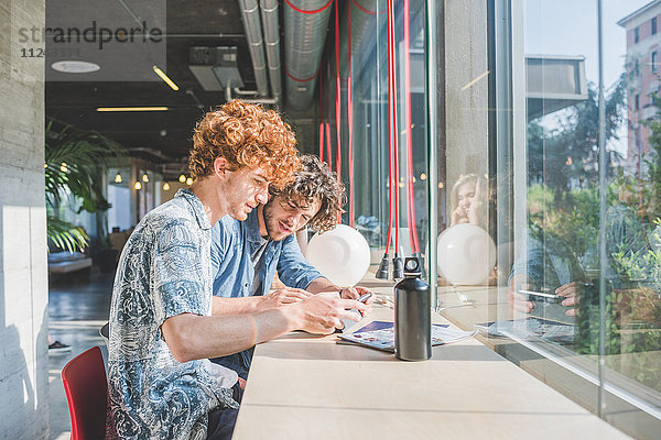 Mitarbeiter bei der Arbeit am Laptop neben der Theke am Fenster