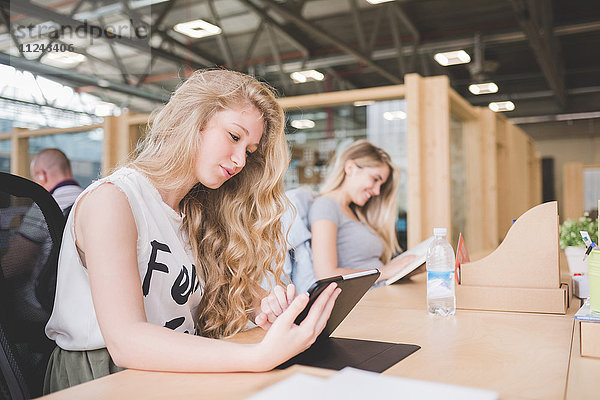 Mitarbeiter  die im Großraumbüro an einem digitalen Tablet arbeiten