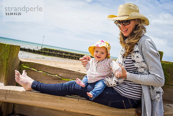 Mittelgroße erwachsene Frau und kleine Tochter sitzen auf einem Strandbuggyne  Ferring Beach  West Sussex  UK