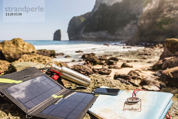 Solarbatterieladegerät und Smartphone am Strand  Südküste  Nusa Penida  Indonesien