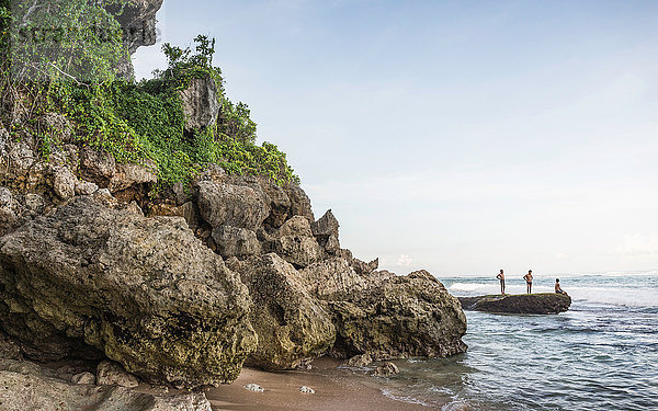 Drei Männer auf Küstenfelsen am Panawa Beach  Bali  Indonesien